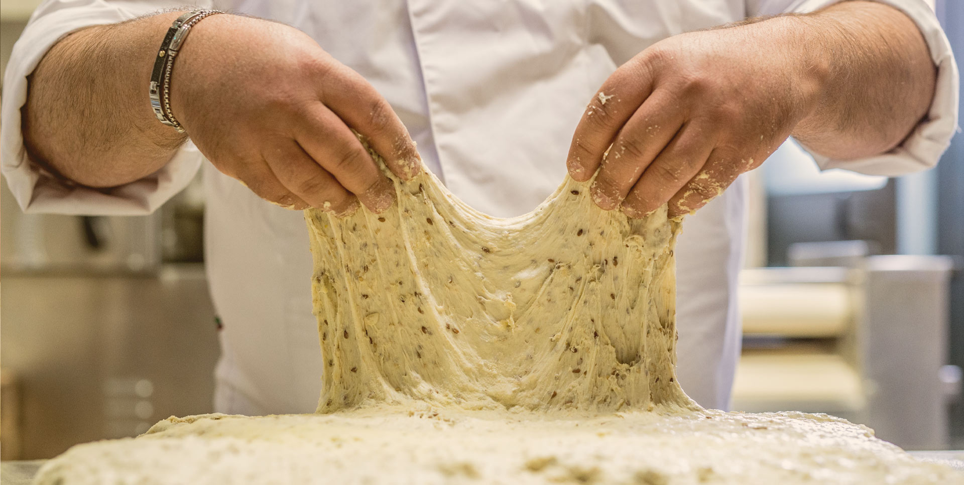 Mani che lavorano un impasto di pane, preparazione artigianale del pane.
